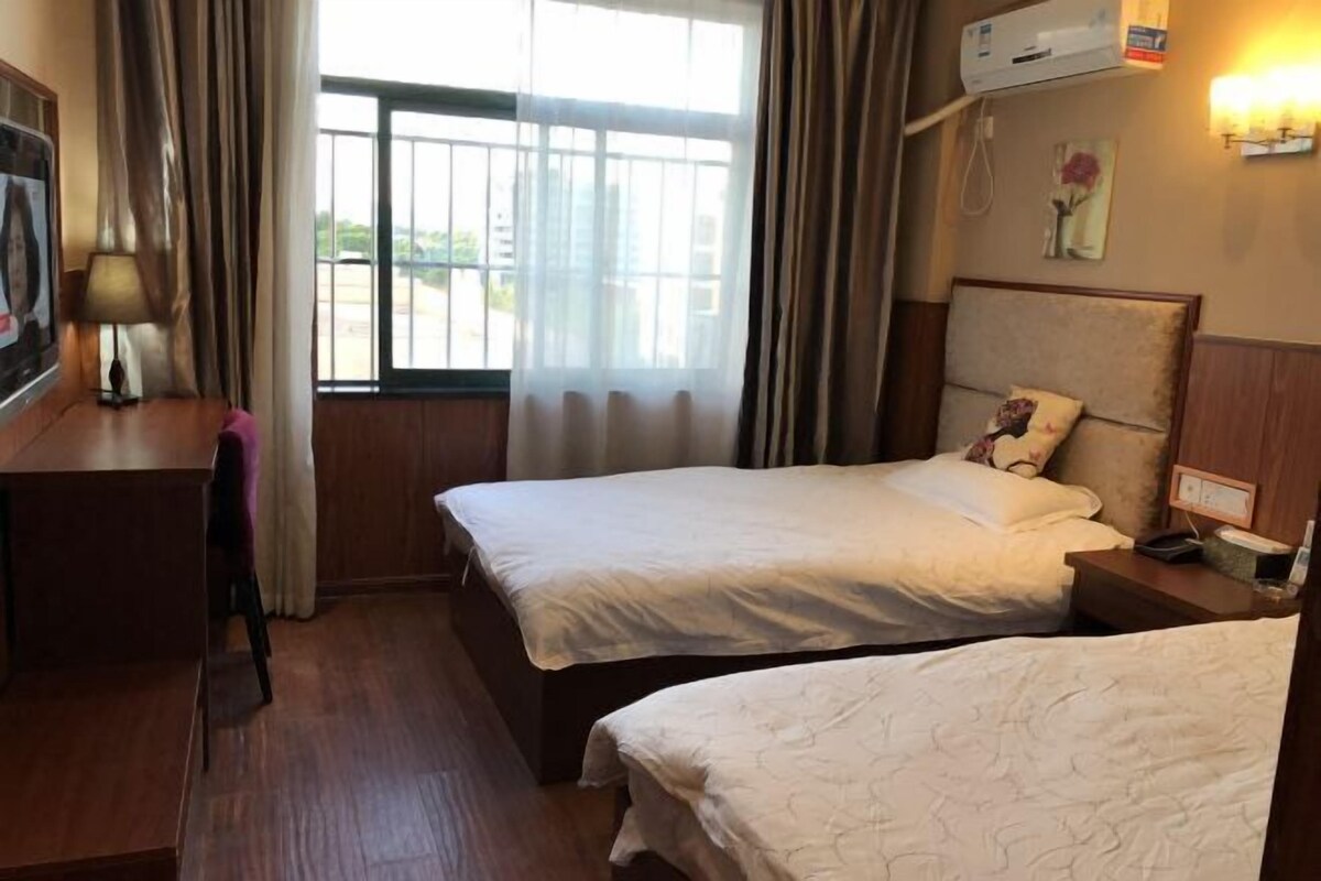 Habitación de hotel con dos camas, un escritorio, una silla y una ventana con cortinas.