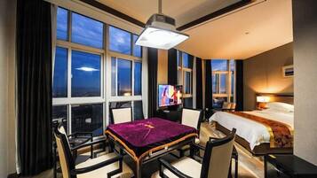 A hotel room with a dining area, a bed, and a television.