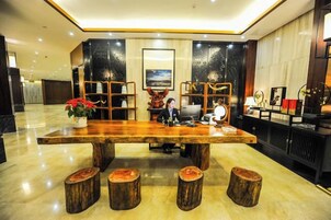 Un área de recepción con mostrador de madera, taburetes para sentarse y un jarrón grande con flores rojas.
