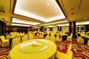 Un salón de banquetes con mesas redondas, sillas y piso alfombrado.