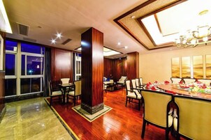 Un vestíbulo de hotel con comedor, ventanas amplias y un candelabro.