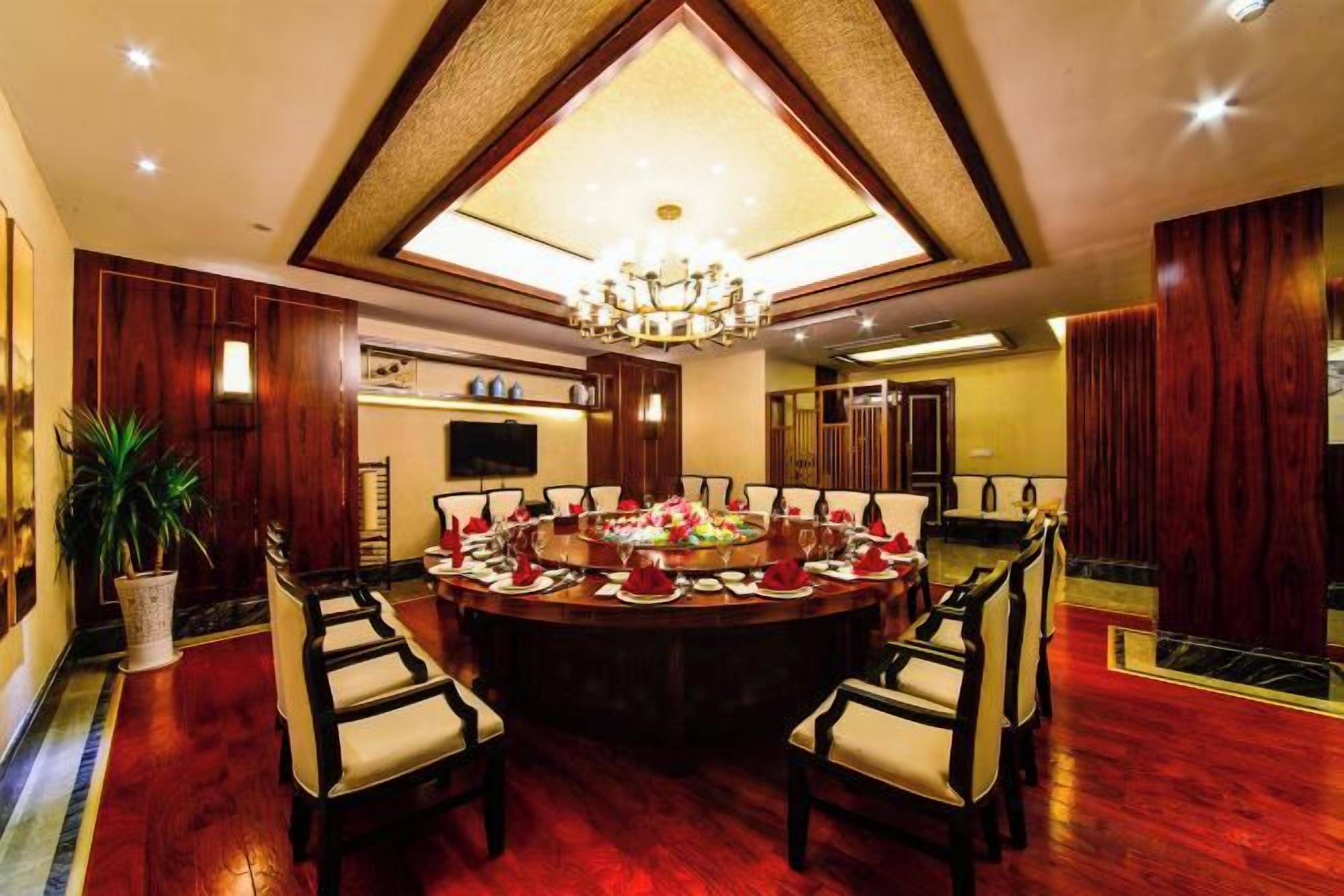 A formal dining room with a large round table, multiple chairs, and a chandelier.