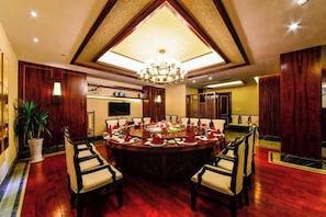 A formal dining room with a large round table, multiple chairs, and a chandelier. - Jin Du International Hotel (Langxi)