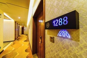 Ein Hotelgang mit Teppichboden, einer Holztür und einem an der Wand befestigten Schild mit der Nummer 1288.