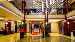 A hotel lobby with a polished marble floor, a central circular light fixture, and a reception desk. - Jin Du International Hotel (Langxi)