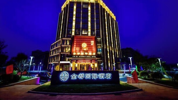 A hotel with a prominent sign in front, featuring a large illuminated display and a traditional Chinese character logo. - Jin Du International Hotel (Langxi)