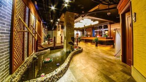 A hotel lobby with a koi pond, wooden decor, and a reception desk. - Jin Du International Hotel (Langxi)