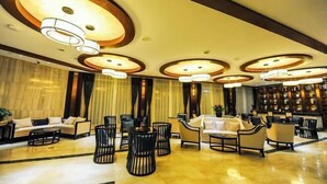 A spacious lobby with a modern design, featuring a central seating area with sofas and chairs, a reception desk, and a decorative ceiling with circular light fixtures. - Jin Du International Hotel (Langxi)
