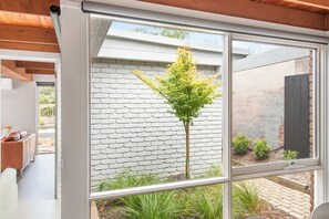A modern interior with a large window overlooking a brick wall and a small tree.