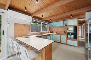 A modern kitchen with wooden beams, a central island, and a view to the outdoors.