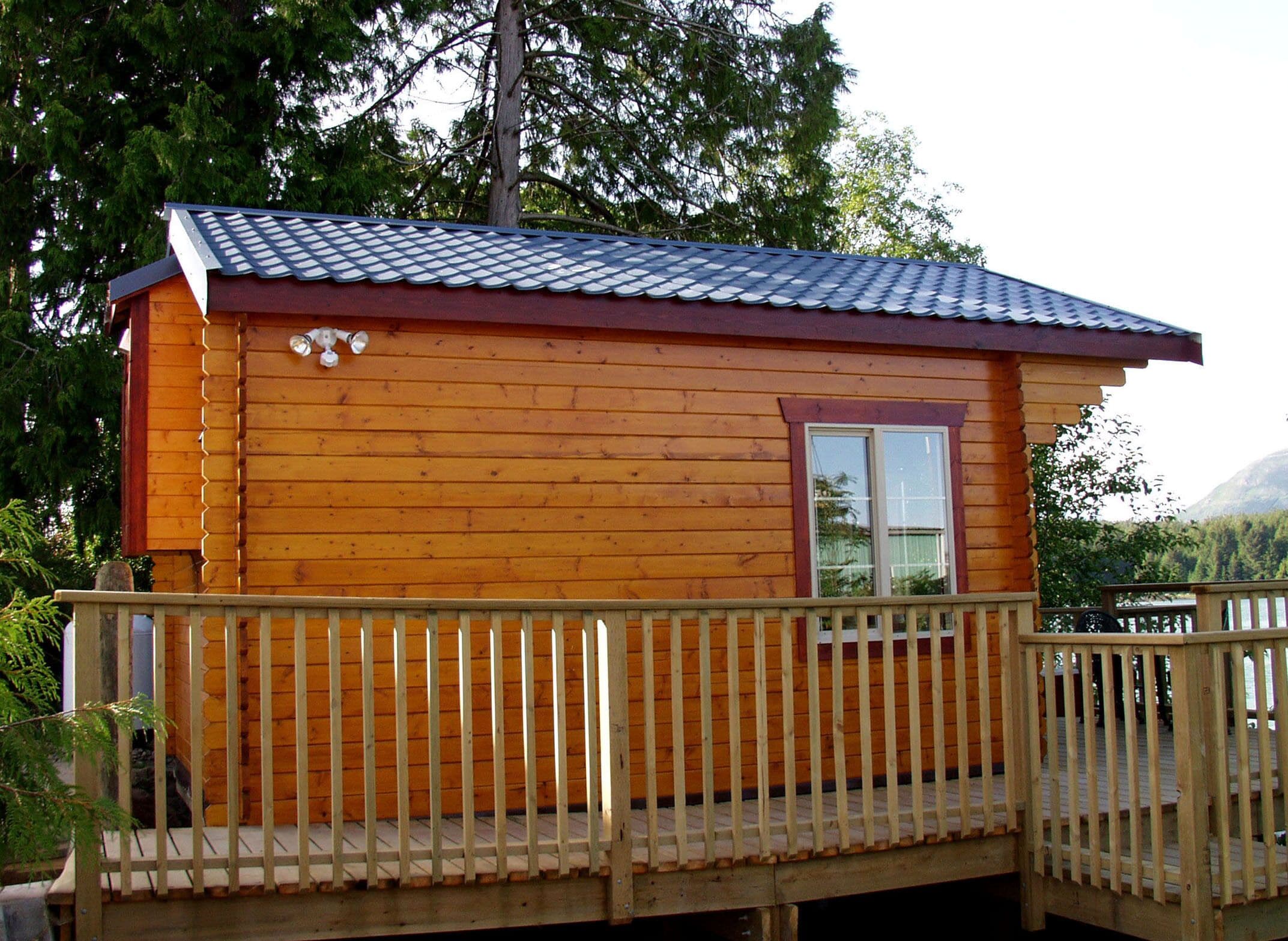 Een houten chalet met een balkon en een raam.