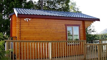 Een houten chalet met een balkon en een raam.