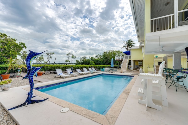 Relax by the pool surrounded by lounge chairs and a decorative sculpture.