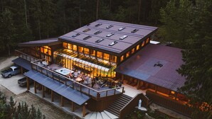 A multi-story lodge with a large deck area, hot tub, and outdoor seating. - New Denver Lodge – Relax, Unwind & Reconnect (New Denver)