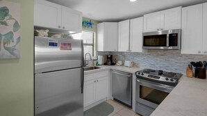 A compact kitchen with white cabinets, a stainless steel refrigerator, a microwave, a stove, and a coffee maker. - Gulf Views*Private Beach*Dog Friendly*Beach Gear (Destin)