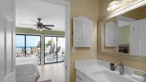 A bathroom with a large mirror, a ceiling fan, and a view of a balcony with chairs. - Gulf Views*Private Beach*Dog Friendly*Beach Gear (Destin)