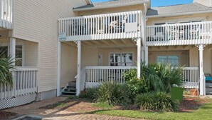 A two-story building with a white exterior, a covered front porch, and a small garden area. - Gulf Views*Private Beach*Dog Friendly*Beach Gear (Destin)