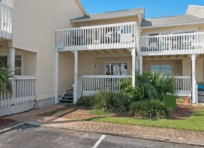 A two-story building with a white exterior, a covered front porch, and a small garden area.