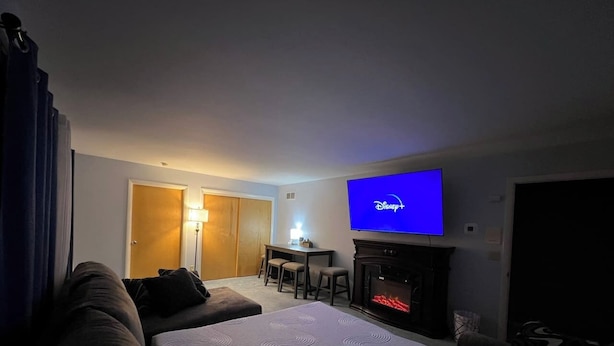 Une chambre d’hôtel dotée d’un grand téléviseur à écran plat, d’une cheminée, d’un canapé, d’une table à manger avec des chaises et d’un petit coin cuisine.