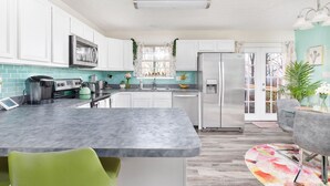 A modern kitchen with white cabinets, a central island, and a stainless steel refrigerator.