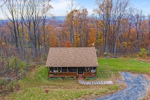 Une cabane dotée d’un porche, entourée d’arbres aux feuilles d’automne.