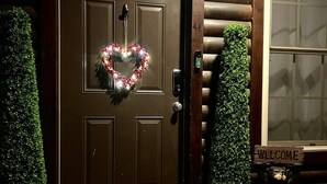 A wooden door with a heart-shaped wreath, a welcome sign, and a mailbox.
