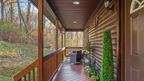 A wooden deck with a railing, a seating area with a table and chairs, and a potted plant arrangement.
