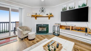 Un salon avec une cheminée, un téléviseur et un balcon.