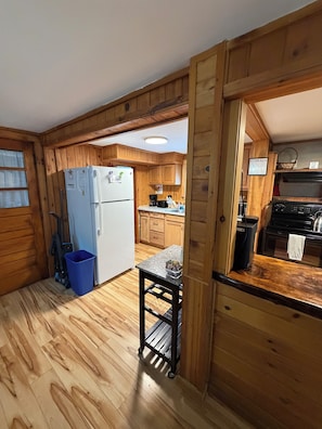 Eine Küche mit Holzwandverkleidung, einem Kühlschrank, einem Herd und Holzschränken.