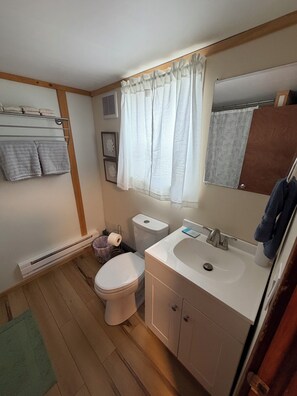 Een bad/douchecombinatie, een haardroger, handdoeken, toiletpapier