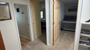 Ein Zimmer mit einem Bett, einem Schreibtisch und einem Bücherregal. Eine Tür führt in einen anderen Raum.