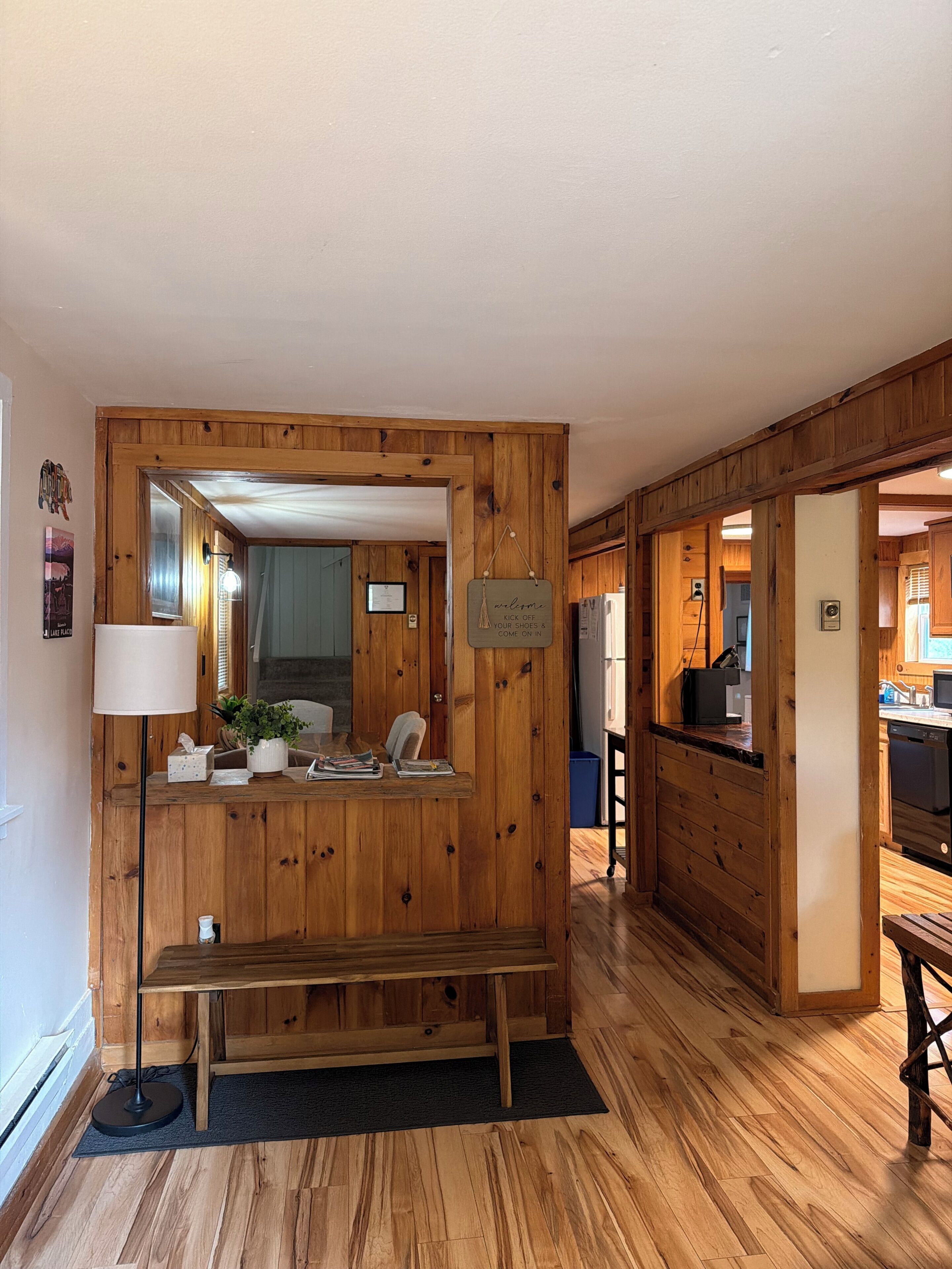 A wooden interior with a bench, a mirror, and a welcome sign.