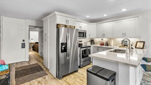 Una cocina moderna con armarios blancos, electrodomésticos de acero inoxidable y encimera de mármol.