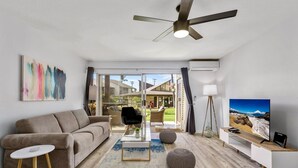 Una sala de estar moderna con sofá, mesa de centro y mueble para televisión.