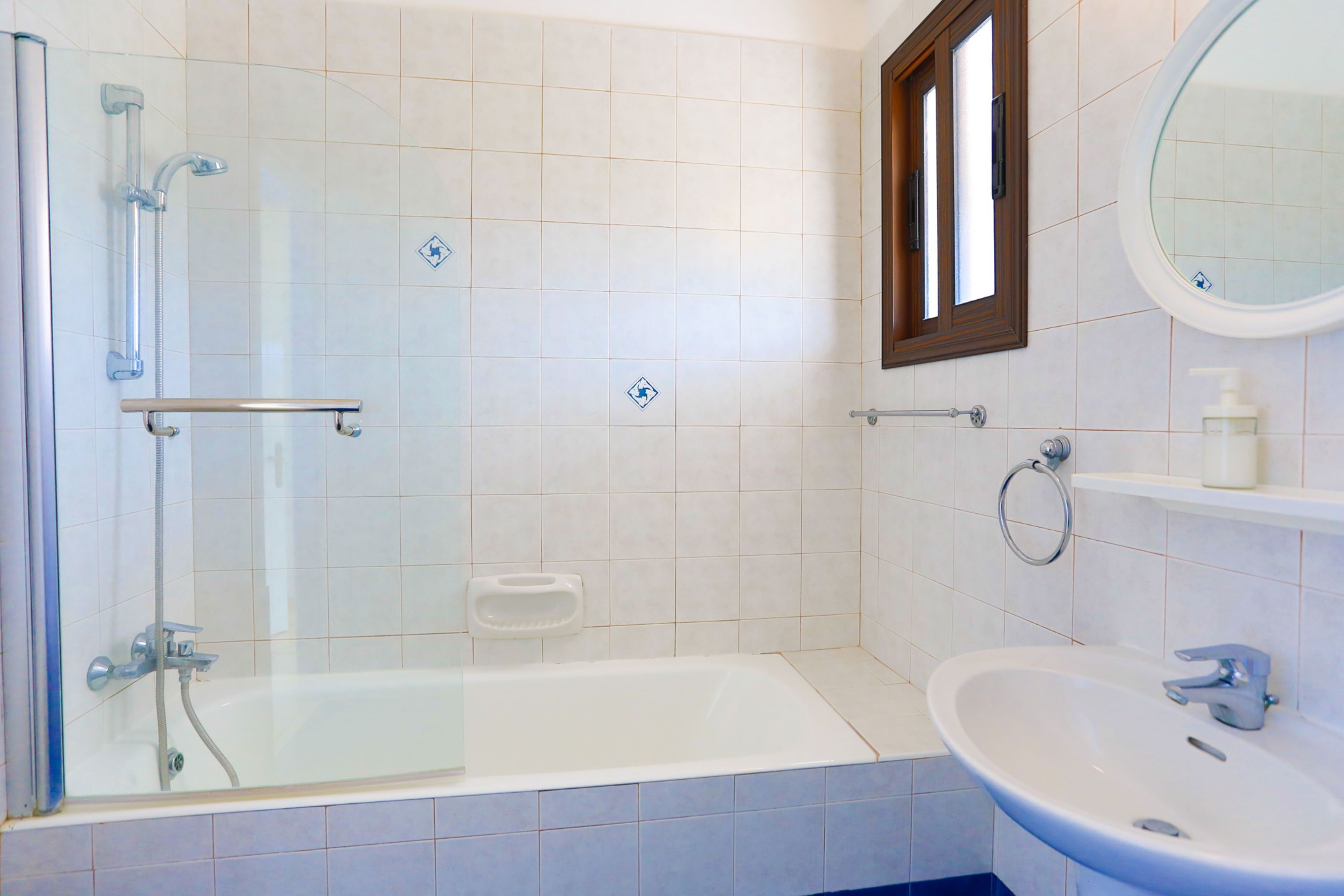 Een badkamer met een douchecabine van glas, een wit bad, een wastafel en een spiegel.