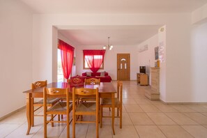 Un coin repas avec une table et des chaises en bois, un canapé rouge et un meuble en bois.