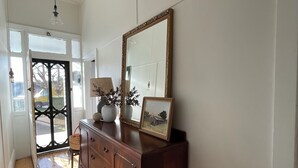 A hallway with a wooden floor, a large mirror, and a cabinet with decorative items. - When a little white house in the country is all that is required! (Maffra)