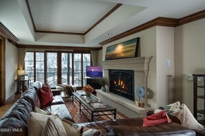 A living room with a fireplace, leather sofa, and a television. - Ritz Carlton Vail #417 4 Bedroom Condo by RedAwning (Vail)