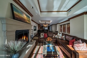 A living room with a fireplace, a sofa set, a coffee table, and a large painting on the wall. - Ritz Carlton Vail #417 4 Bedroom Condo by RedAwning (Vail)
