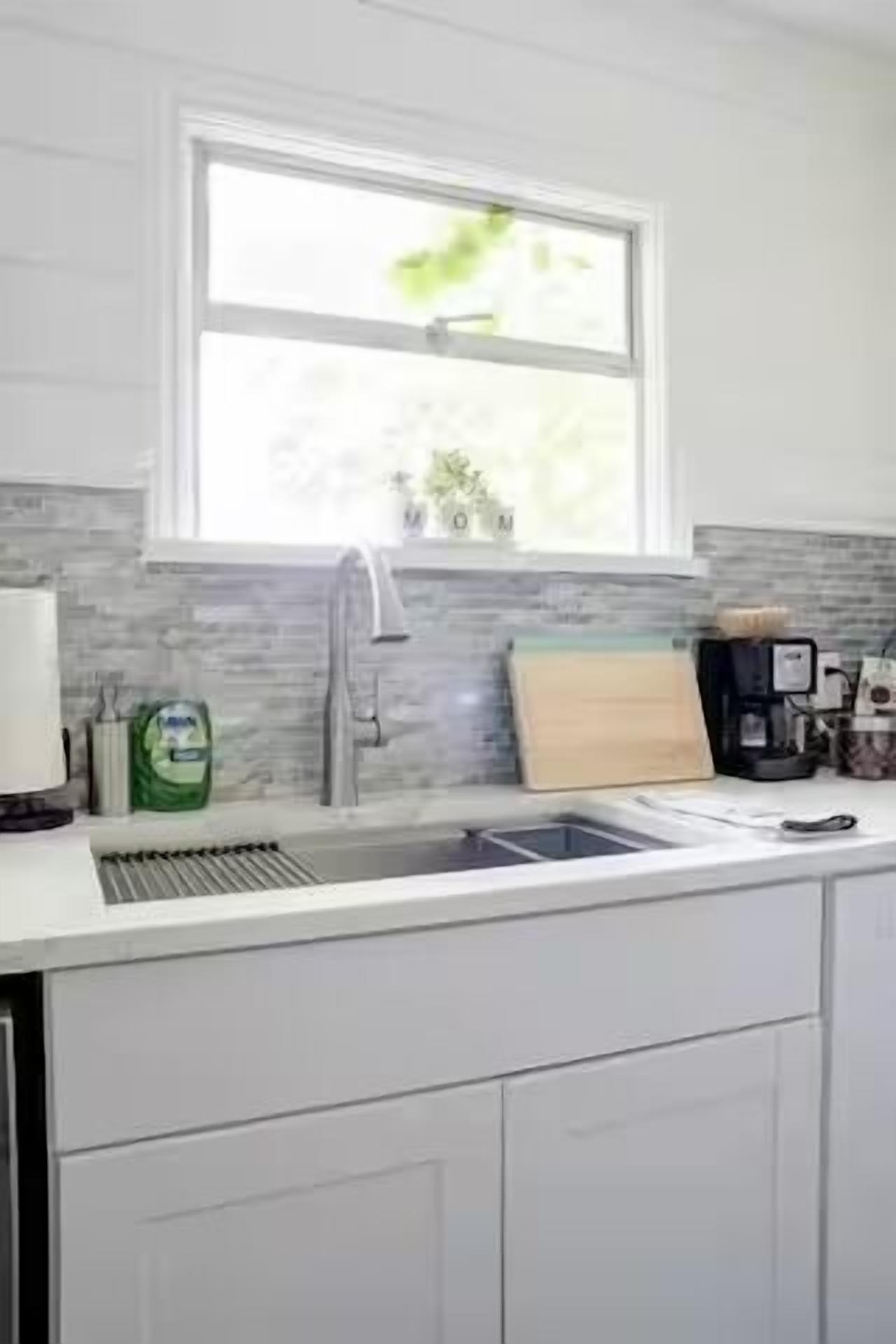 A kitchen with a window above the sink, a coffee maker, and a plant on the windowsill.