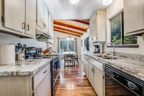 A modern kitchen with wooden cabinets, granite countertops, and a central island. - Blue Lake Springs Gem - Corner  Lot w/ 2 Large Decks, A/C, Shared Pool & Tennis (Arnold)