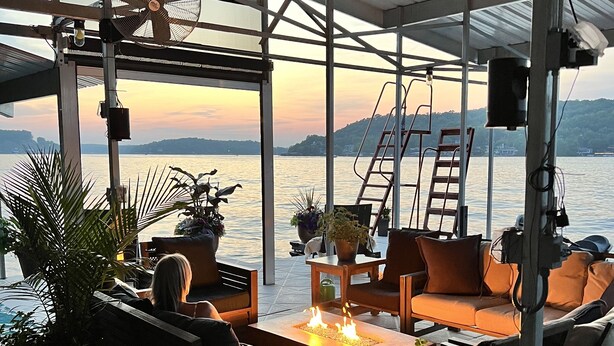 An outdoor seating area with a fire feature, fans, and a view of the water. - BEST dock on lake.  New Hot Tub 2024. 4 BDRM, SLEEP 15.Aargh You Here Yet? (Gravois Mills)