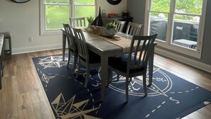 A dining area with a table set for four, a ceiling fan, and large windows with blinds. - BEST dock on lake.  New Hot Tub 2024. 4 BDRM, SLEEP 15.Aargh You Here Yet? (Gravois Mills)