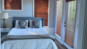 A bedroom with a bed, a nightstand, a lamp, and three windows with blinds. - BEST dock on lake.  New Hot Tub 2024. 4 BDRM, SLEEP 15.Aargh You Here Yet? (Gravois Mills)
