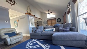 A living room with a sectional sofa, a leather armchair, and a blue rug with an anchor design. - BEST dock on lake.  New Hot Tub 2024. 4 BDRM, SLEEP 15.Aargh You Here Yet? (Gravois Mills)