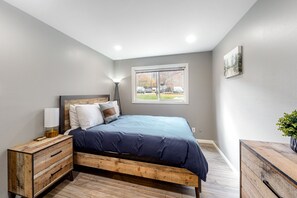 Relax in this serene bedroom with a large bed, nightstand, and potted plant.