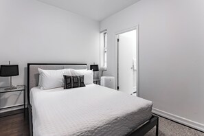 A neatly arranged bedroom with a bed, bedside tables, and a window.