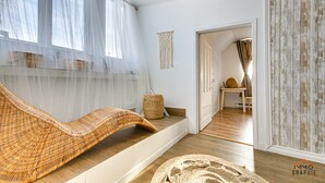 Um quarto com um sofá de vime, uma cesta trançada e um painel de parede em macramé.