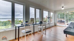 Une pièce spacieuse avec de grandes fenêtres, un plancher en bois, un coin repas avec des chaises et un canapé.
