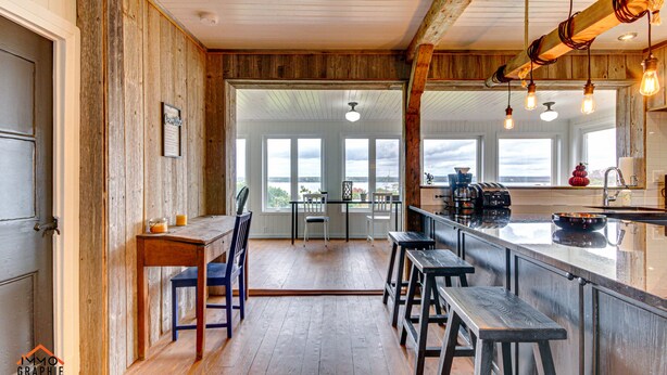 Une cuisine rustique aux murs en bois et dotée d’un grand îlot central avec des tabourets de bar.